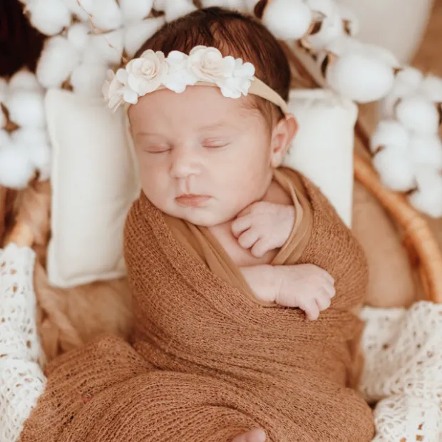 Bébé emmailloté dans un lange terracotta